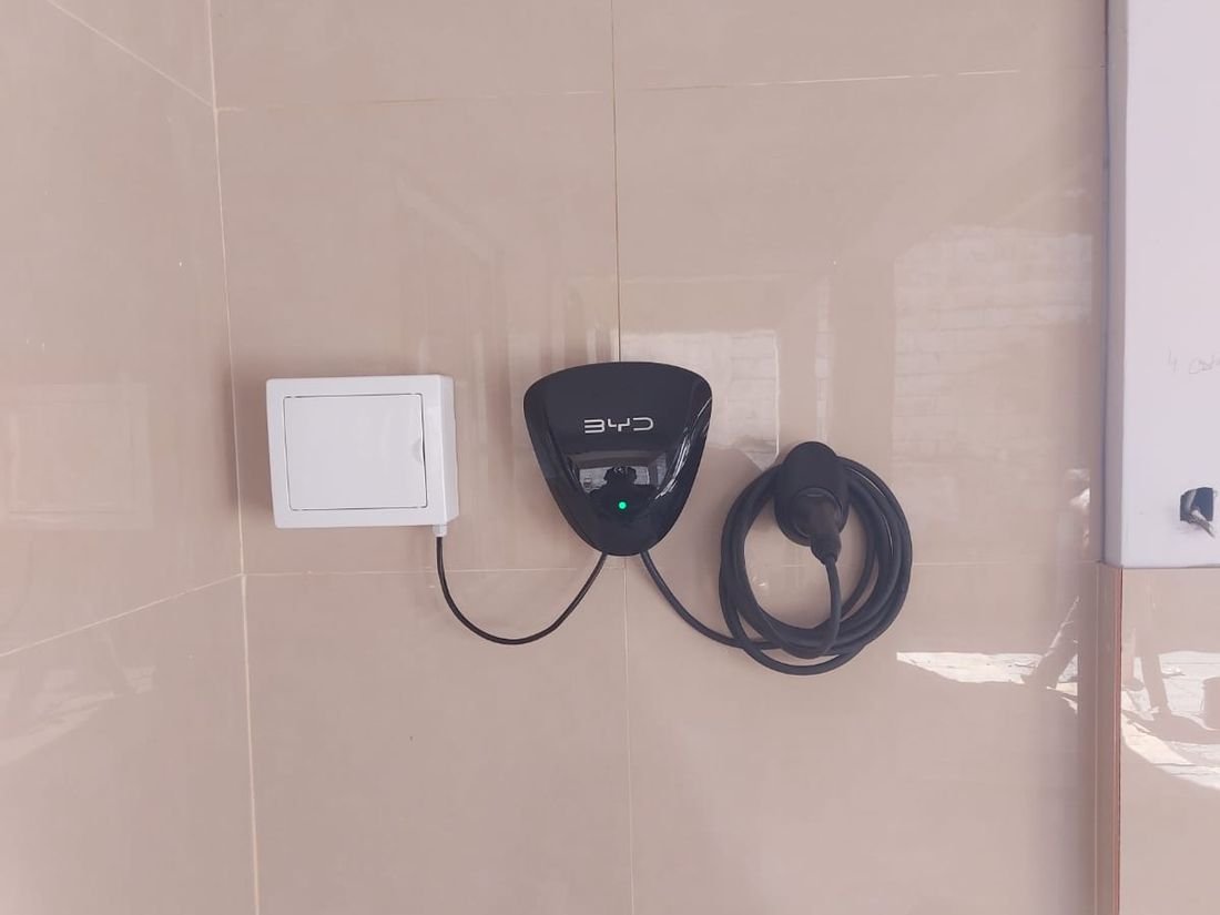 Wallbox BYD instalado em parede, com quadro elétrico dedicado ao lado e cabo Tipo 2 recolhido - Energia Solar Rio